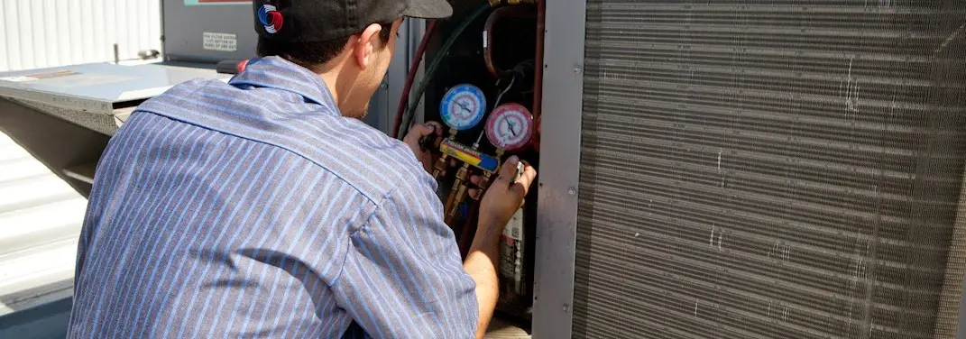 HVAC technician servicing a condenser unit in East Longmeadow